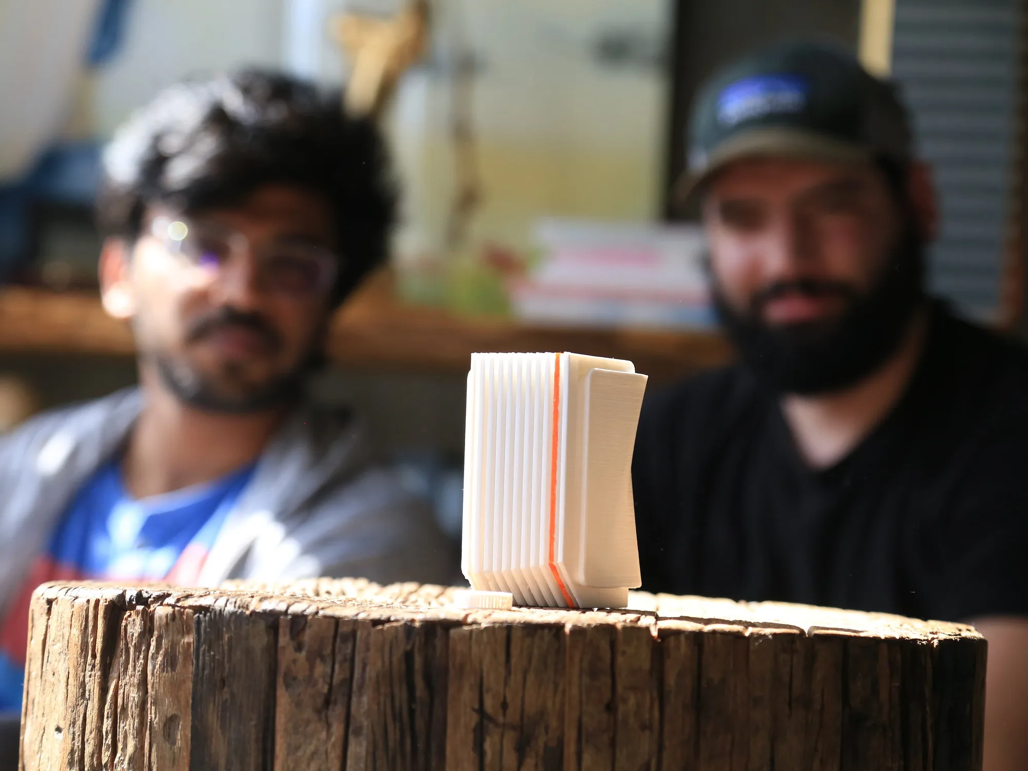 The Epoc prototype on a wooden stump, two people blurred behind it